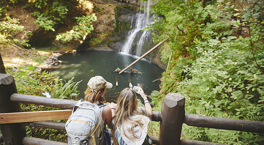 Two Willamette students taking a picture of a waterfall
