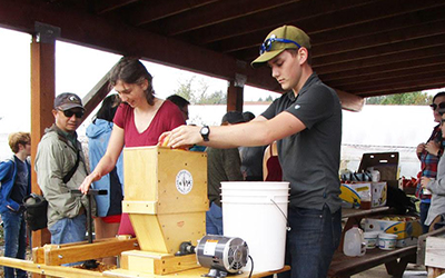 Students use a cider press
