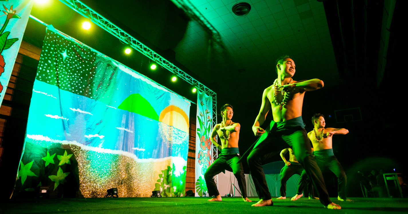 four men dance barefoot onstage in green light