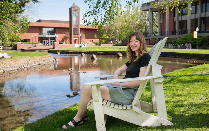 Lily Clancy sits by the Mill Stream on Willamette's Campus.