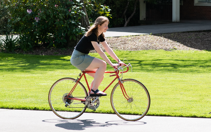 Lily Clancy riding a bike on campus