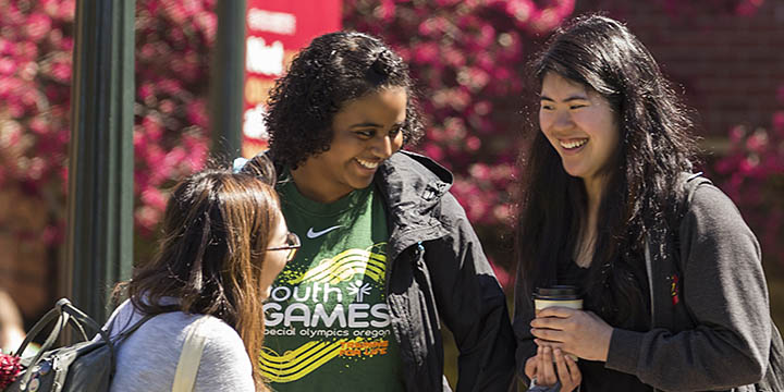 three Willamette students visiting outside on sunny day