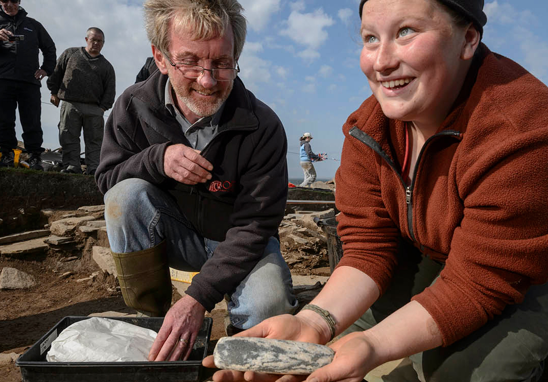 student and professor holding a stone