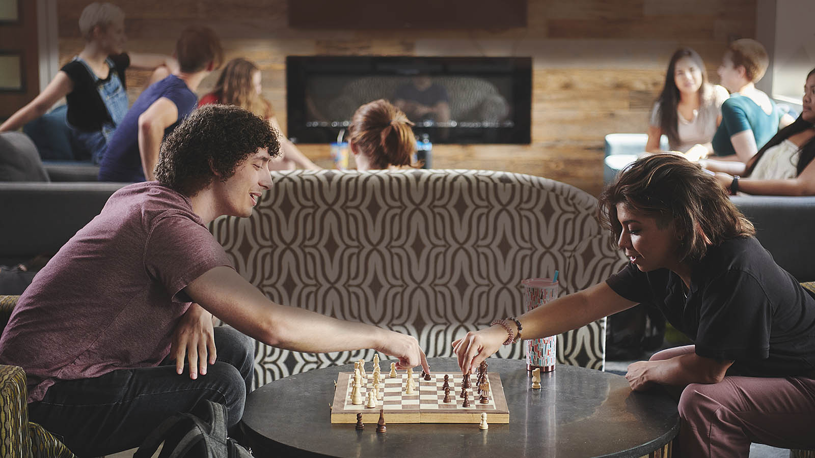 Two Willamette students playing a game of Chess with more students in the background.