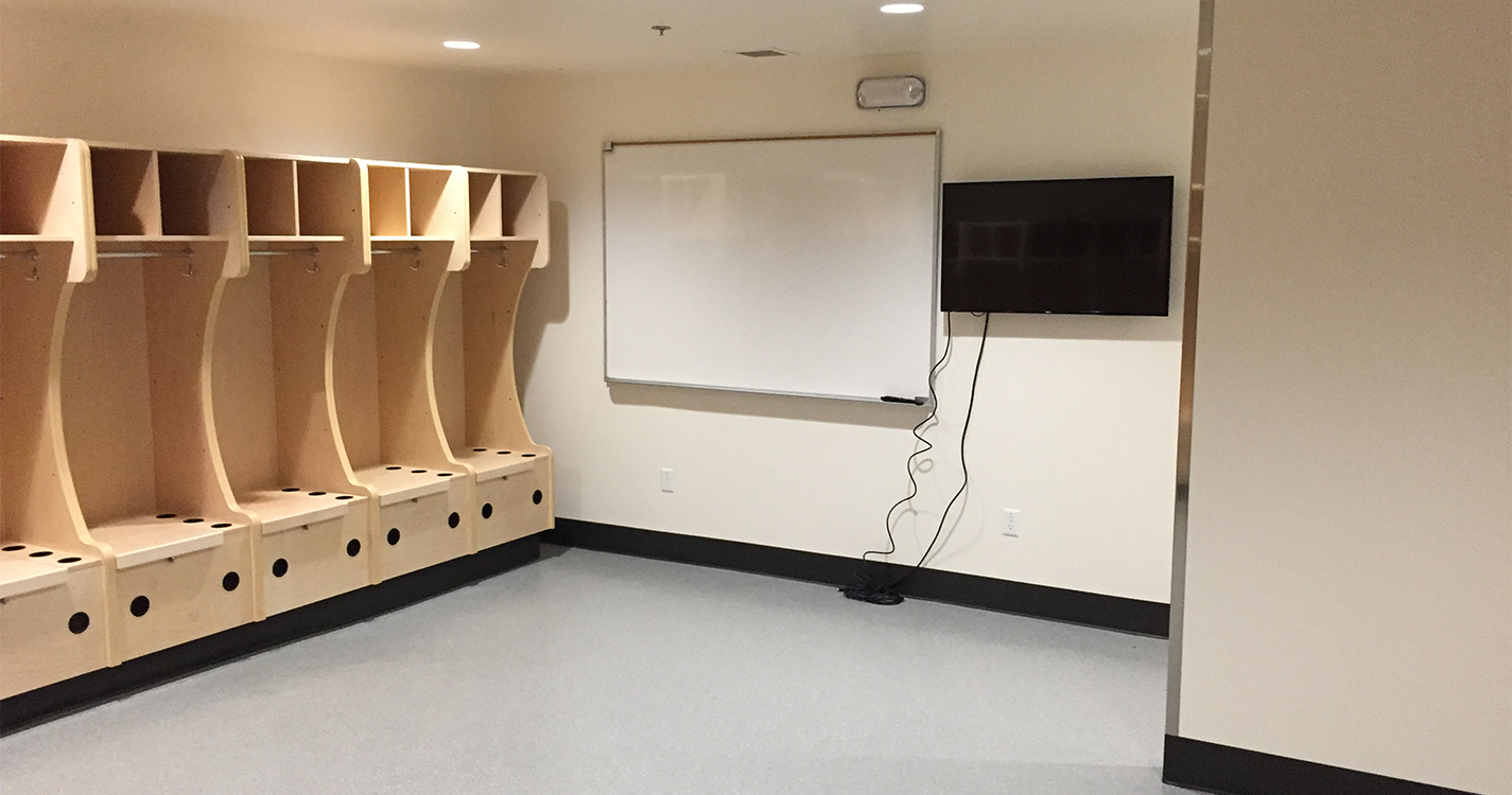 Lockers, whiteboard and flat screen television in the new women’s lacrosse locker room.