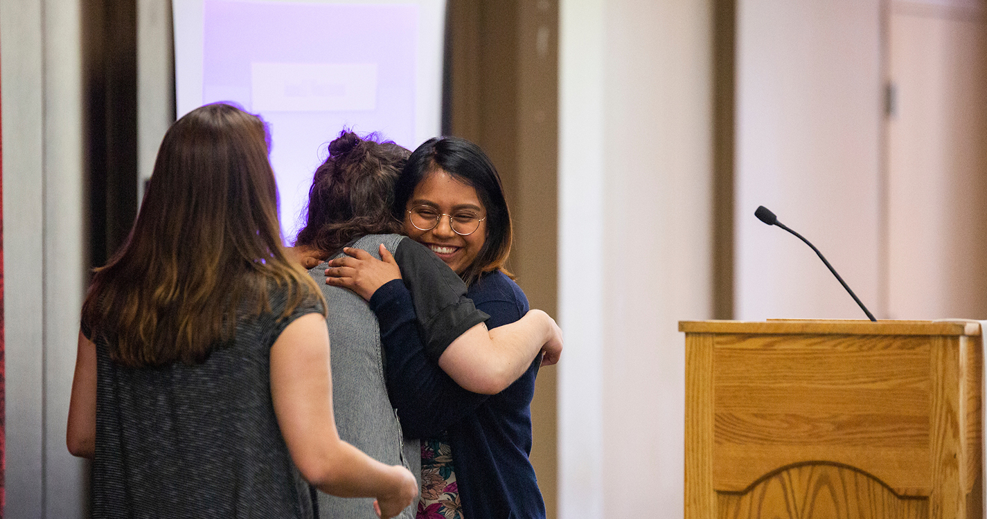 student hugs another after receiving and award