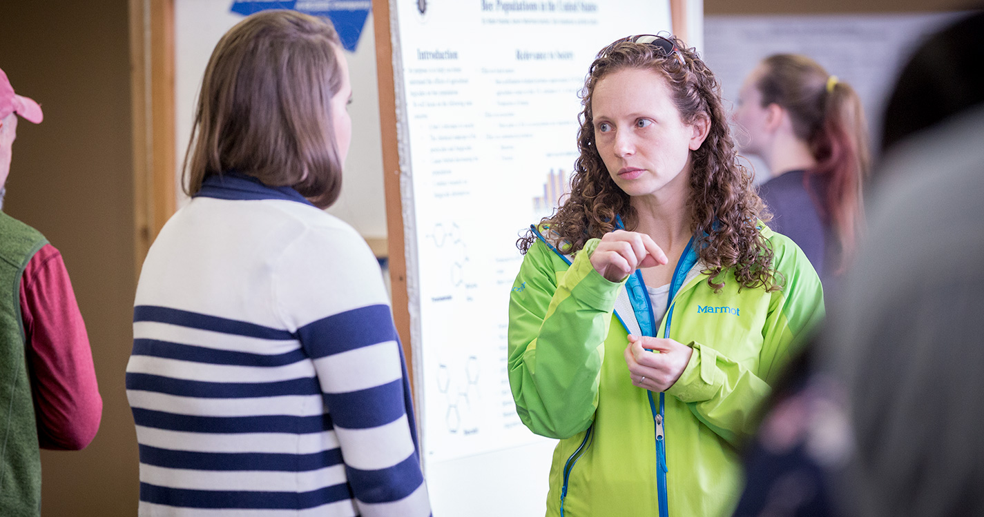 Two people discuss research at Student Scholarship Recognition Day. 