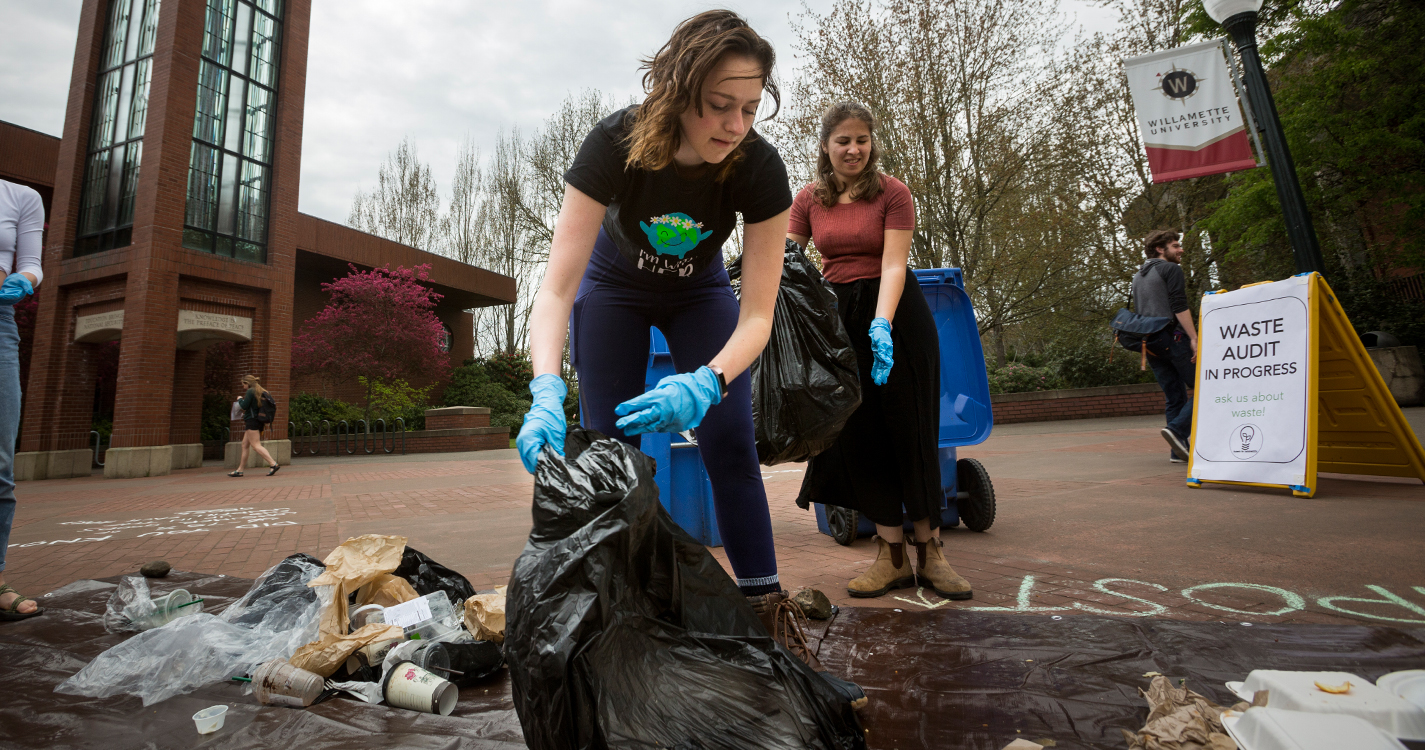 A student wearing rubber gloves sorts trash on a tarp in Jackson Plaza.