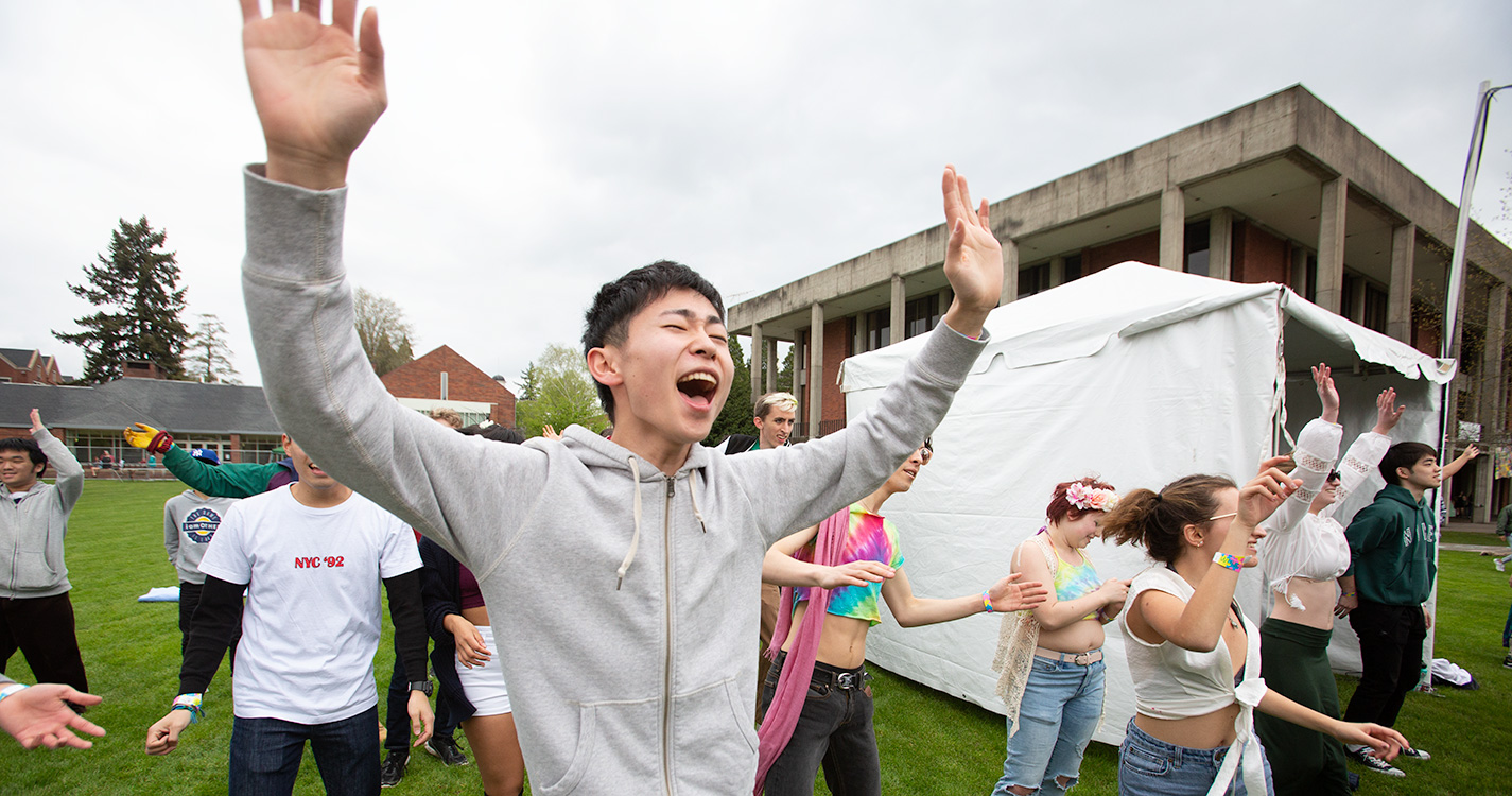 A student raises arms high during "jazzercise" on Brown Field at Wulapalooza.