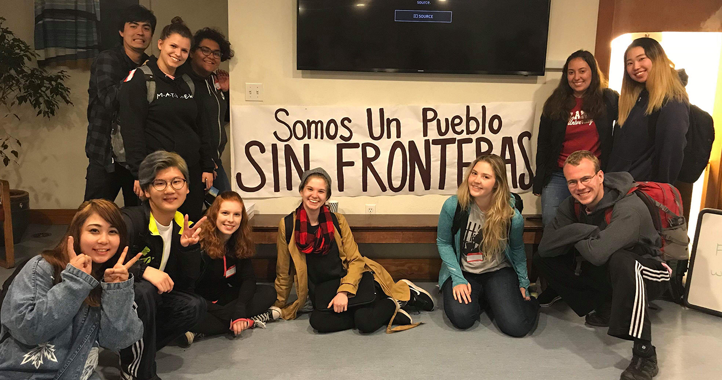 a group of Willamette students poses around a poster that says “Somos un pueblo sin fronteras”