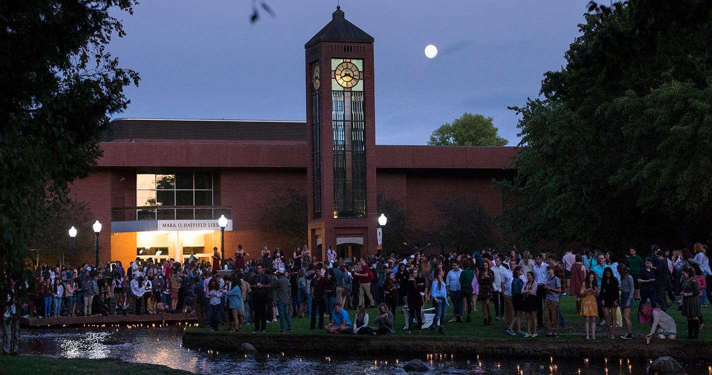 Students line the Mill Stream and fill Jackson Plaza as their candles float downstream.