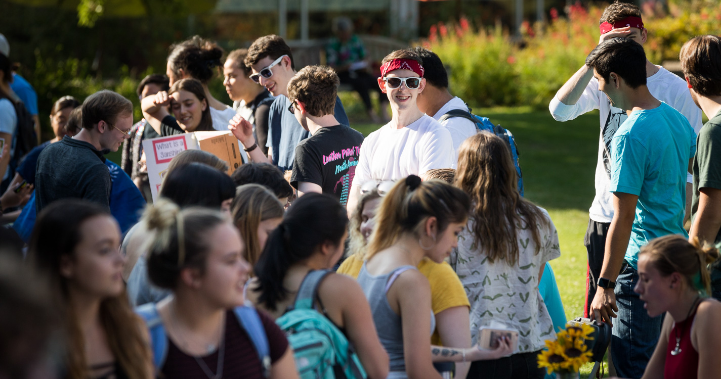 Student wearing sunglasses smiles in a crowd of students