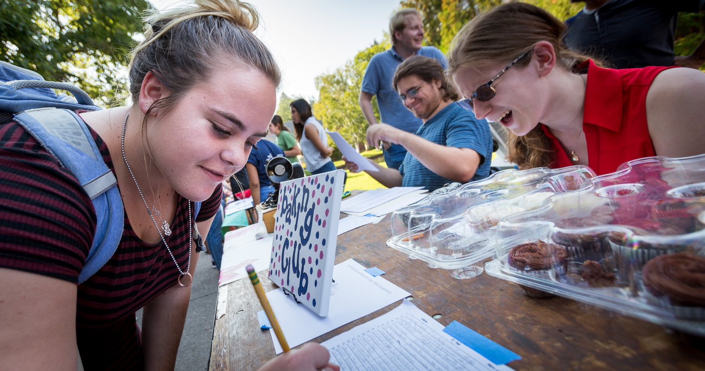 A student signs up at an expo table for Baking Club