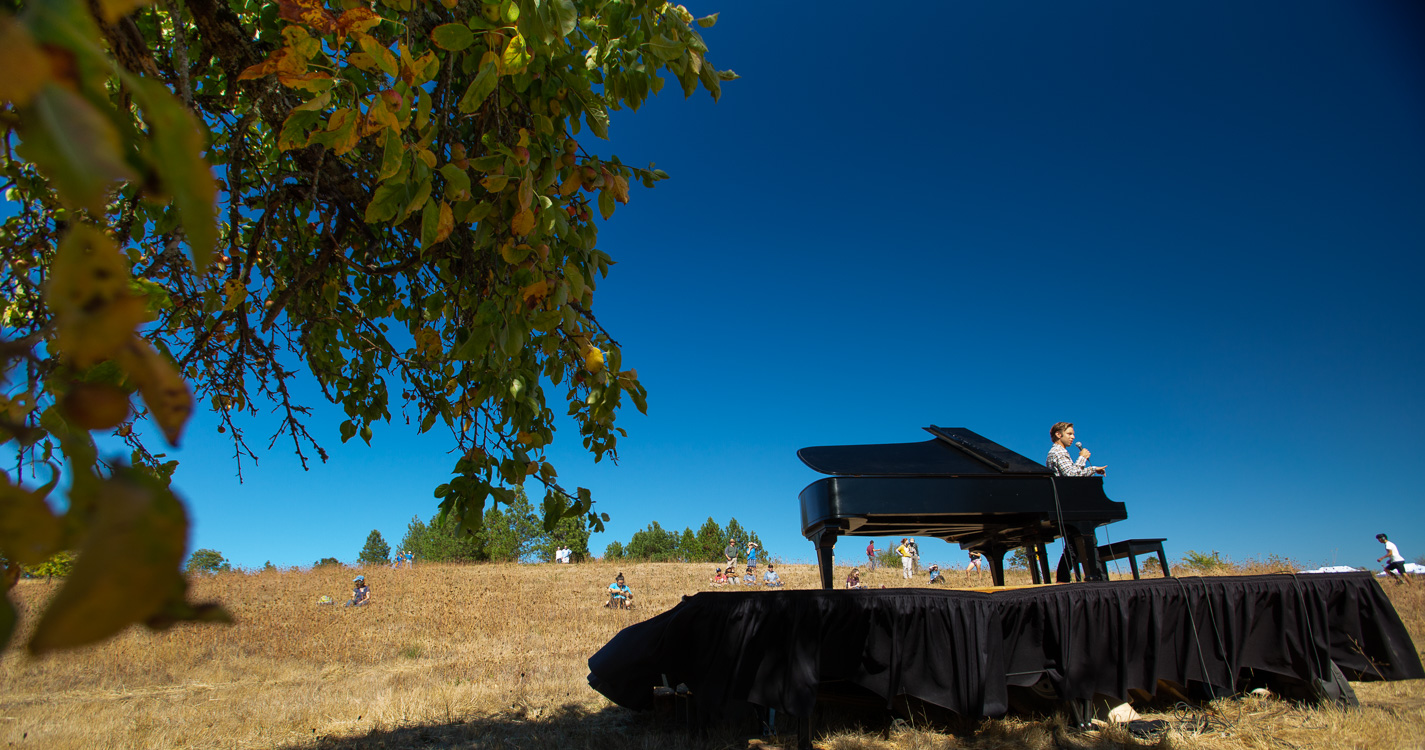 Hunter Noack plays a grand piano in the middle of a field at Willamette's Zena campus