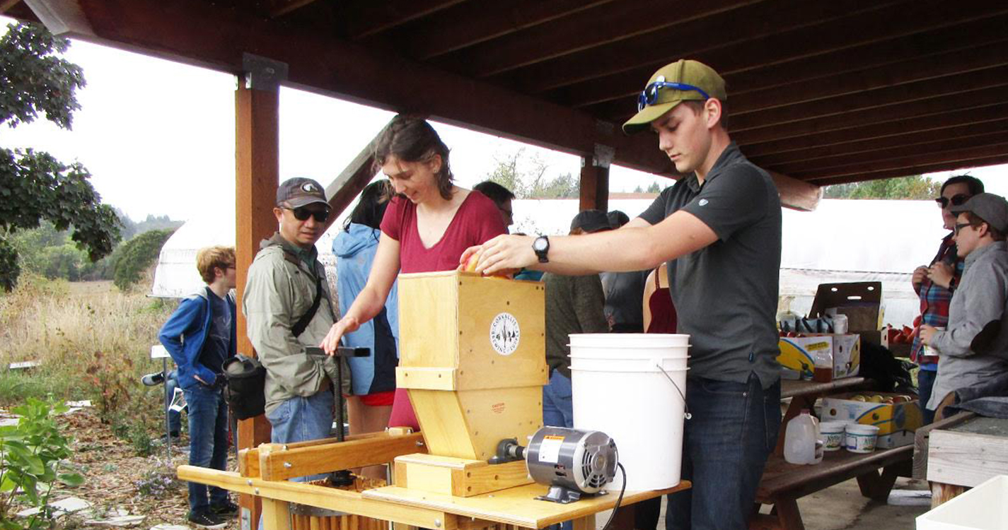 Two students work at a cider press