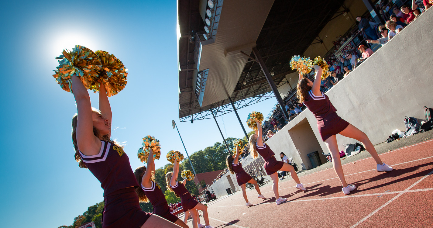 Willamette Cheer team waves pompoms before the crowd at a football game