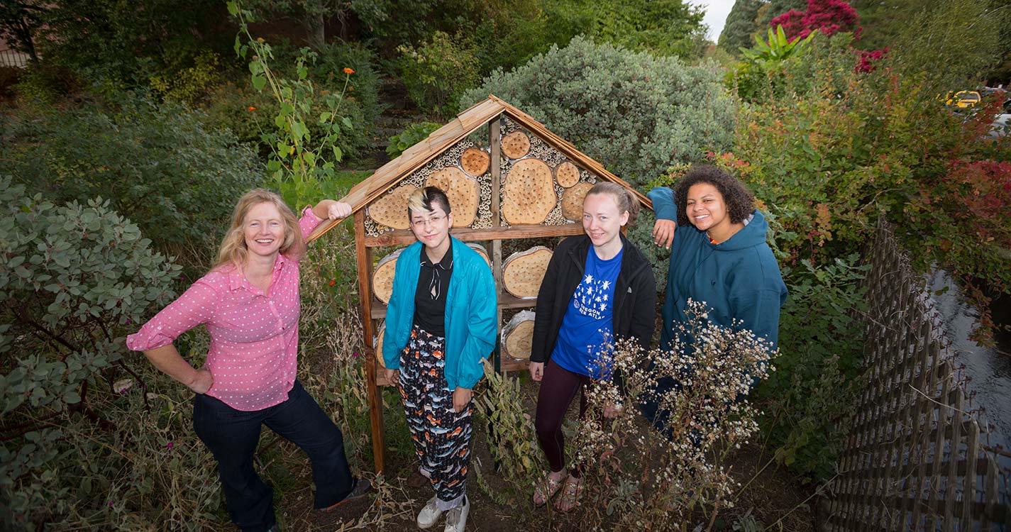 Faculty member, students stand by the bee hotel they built 