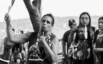 Black and white photo of Winona LaDuke speaking before a crowd