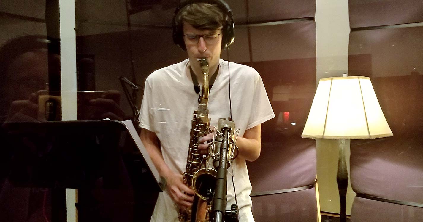 Student plays saxophone in recording booth