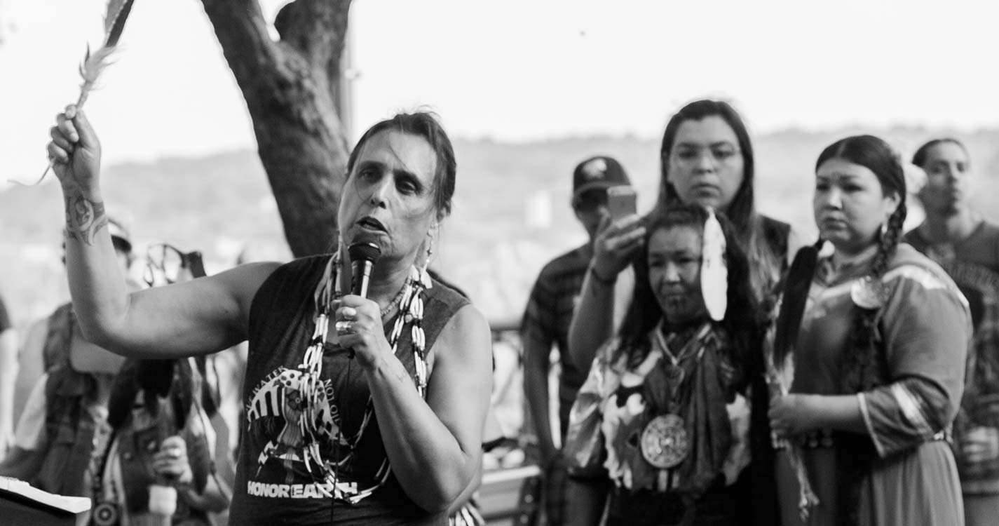 Black and white photo of Winona LaDuke speaking before a crowd