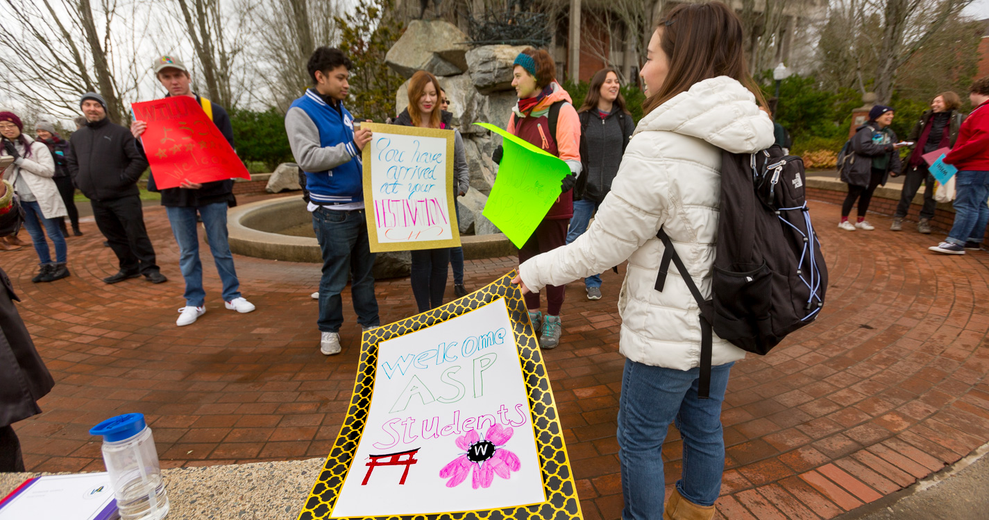 Student disembark buses, while Willamette community member welcome them with colorful signs