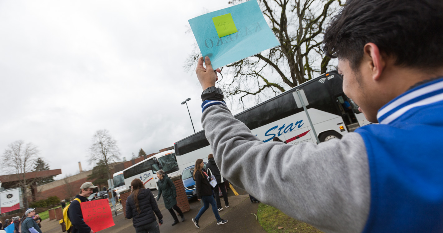 Student disembark buses, while Willamette community member welcome them with signs