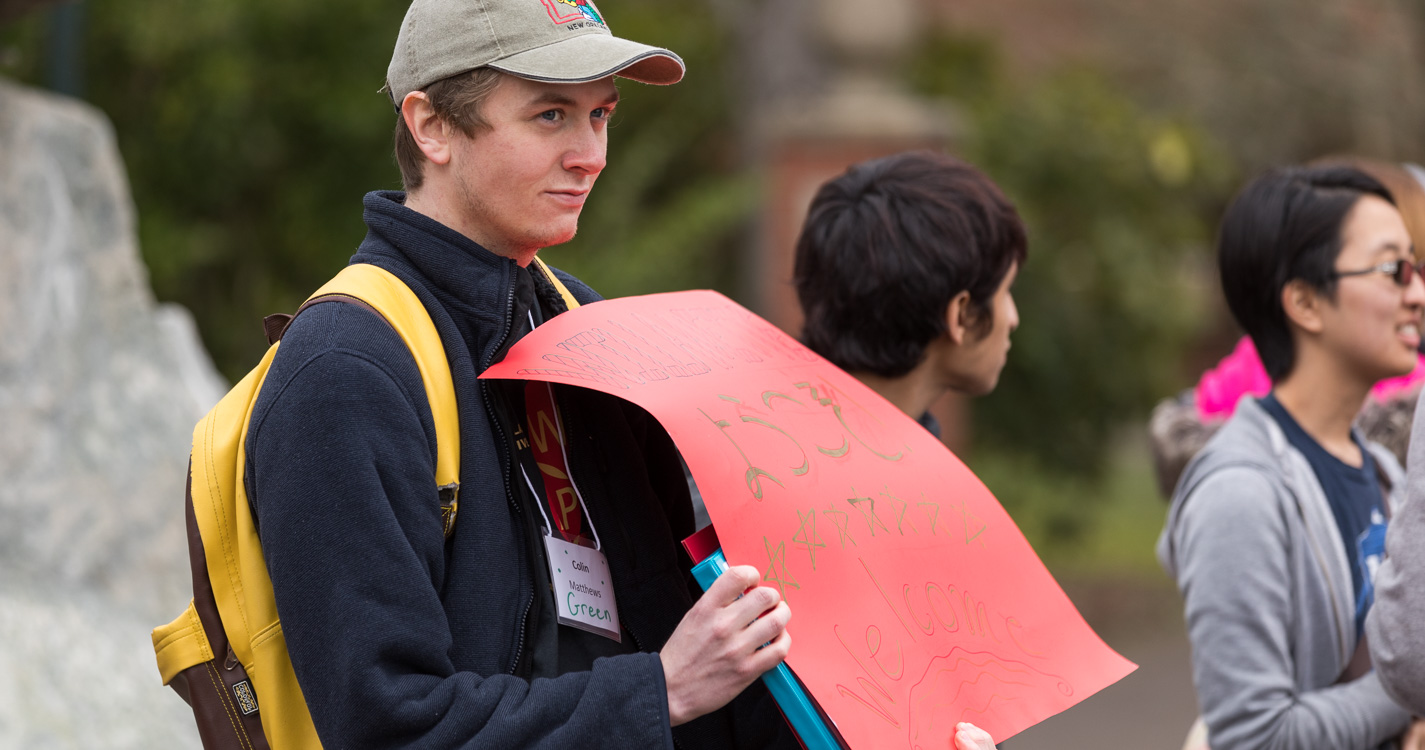 student holding red welcome sign