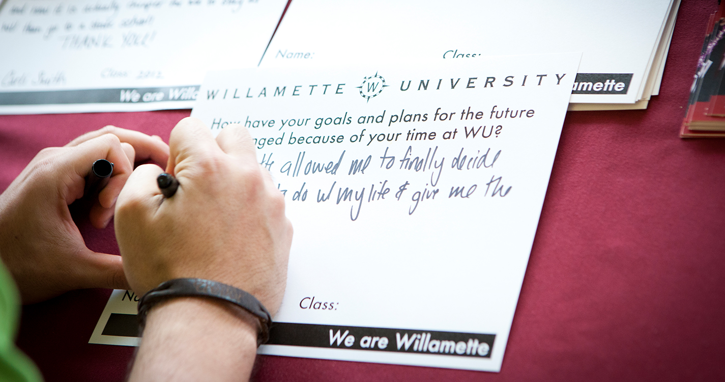 close-up of student's hand writing thank you note to a donor