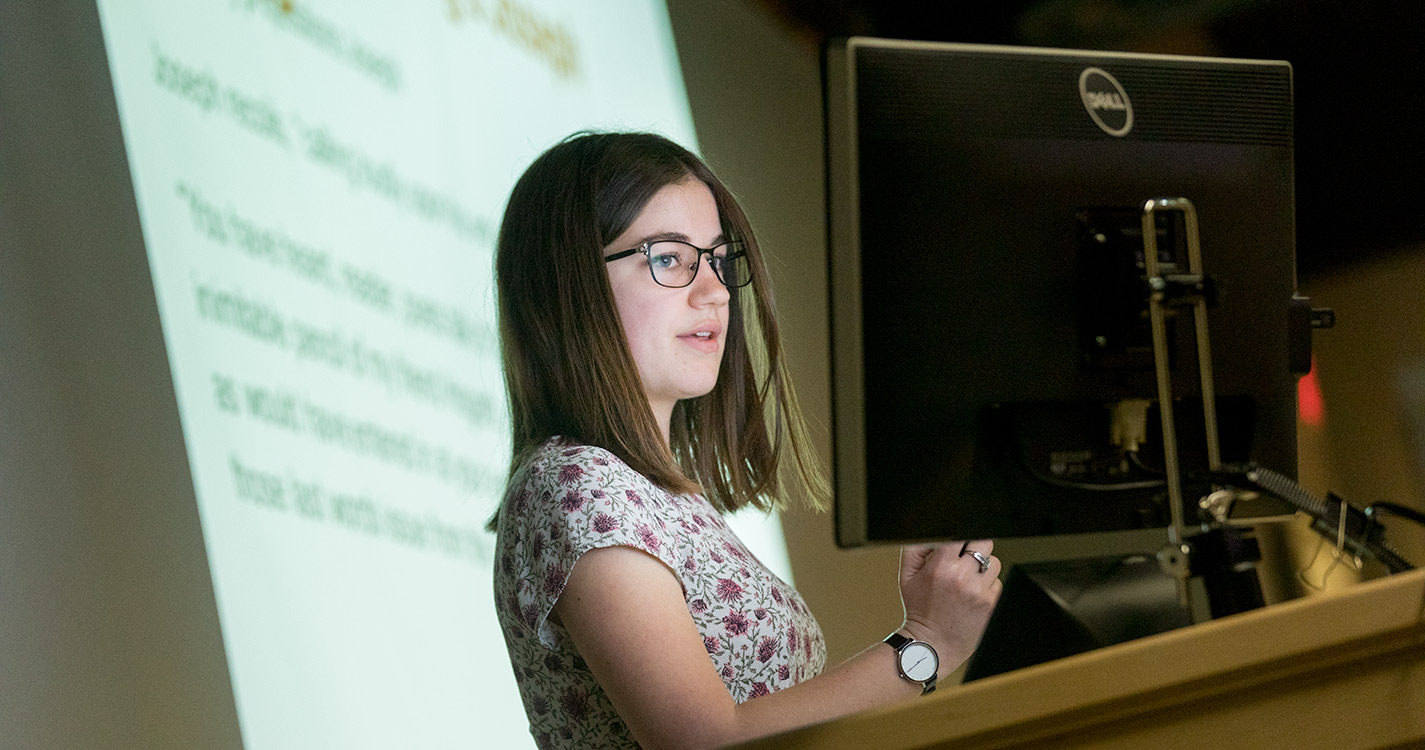 Student stands at a computer making presentation