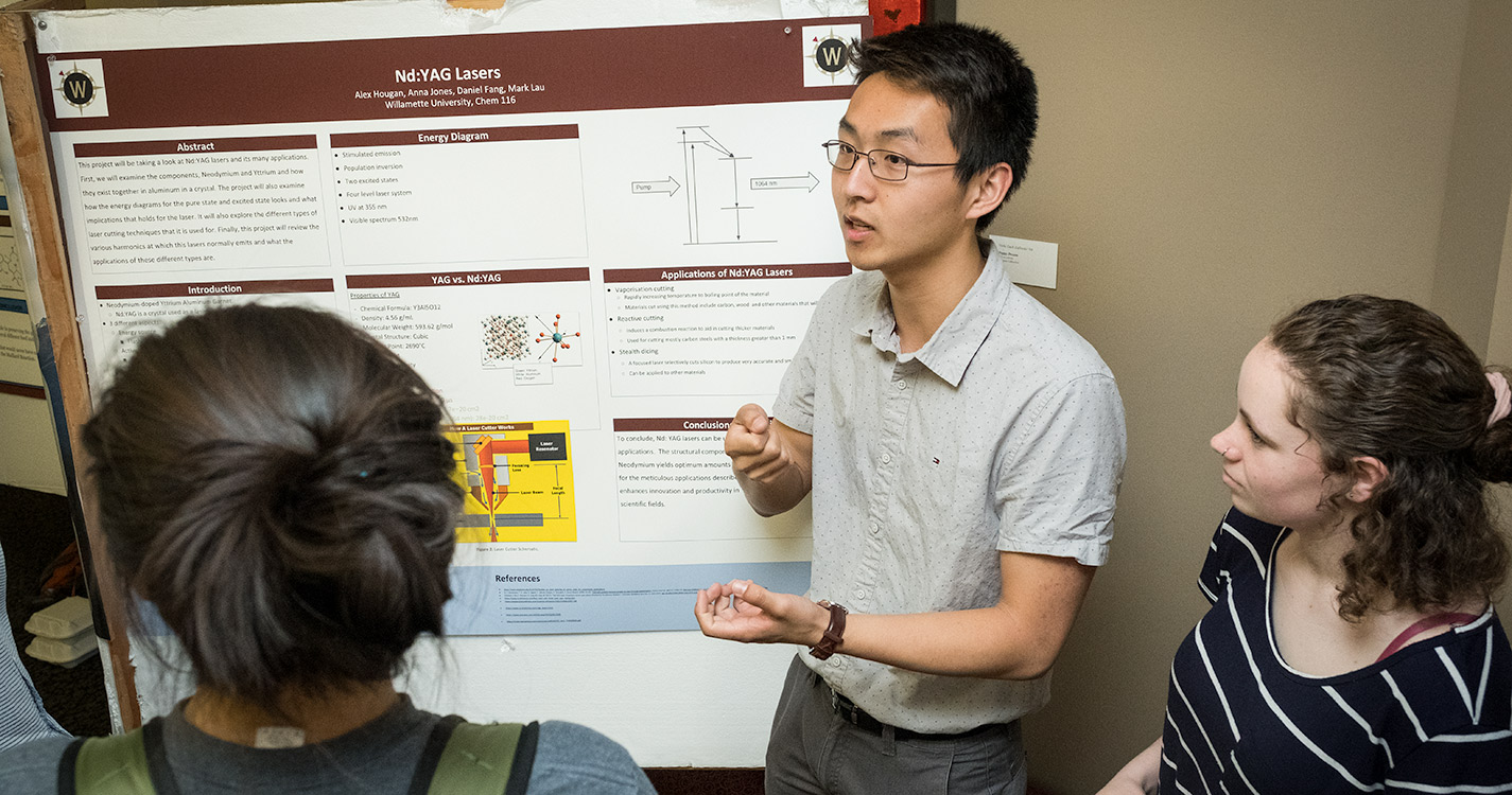 Student speaks and stands before a poster of research
