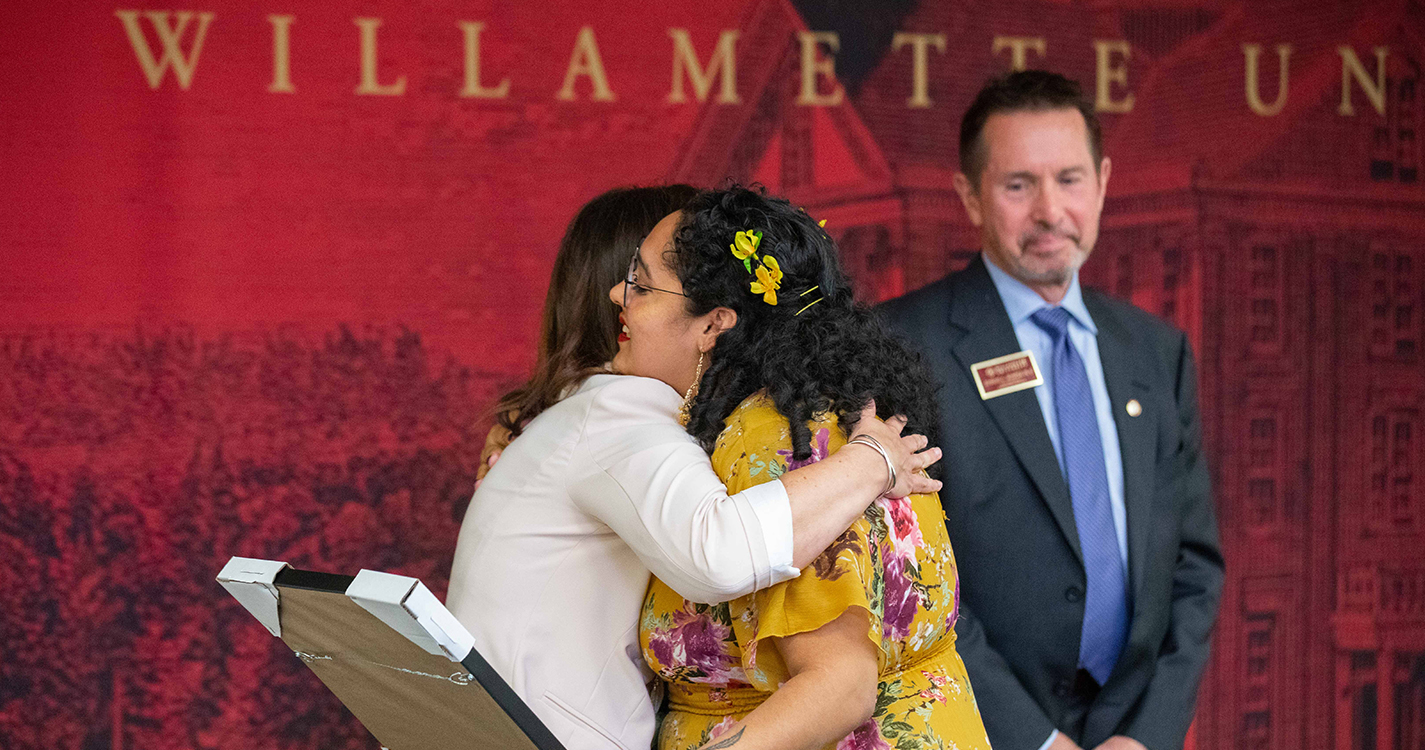 Student receives hug from staff member when receiving award
