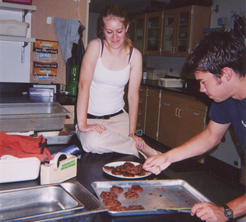 Alex Compton ’06 removes cookies from a pan in a science lab as Kara Michels ’06 watches