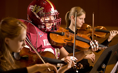 Student wearing a football costume plays a violin