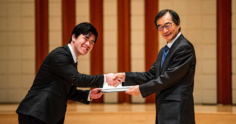 Student shakes TIUA President, Hiroshi Takahashi's hand while receiving their certificate.