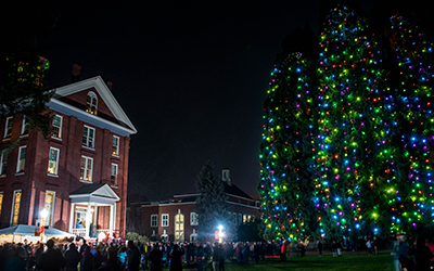 Waller Hall at night next to Star Trees illuminated by colorful holiday lights