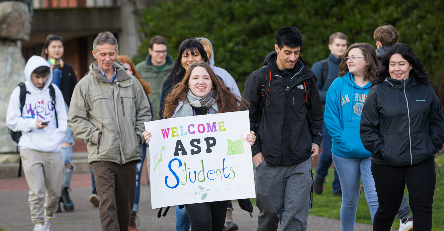 Crowd of students and employees, one holding a sign saying "Welcome ASP Students"