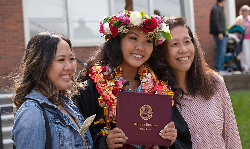 A Willamette student poses for a photo at Commencement with family.
