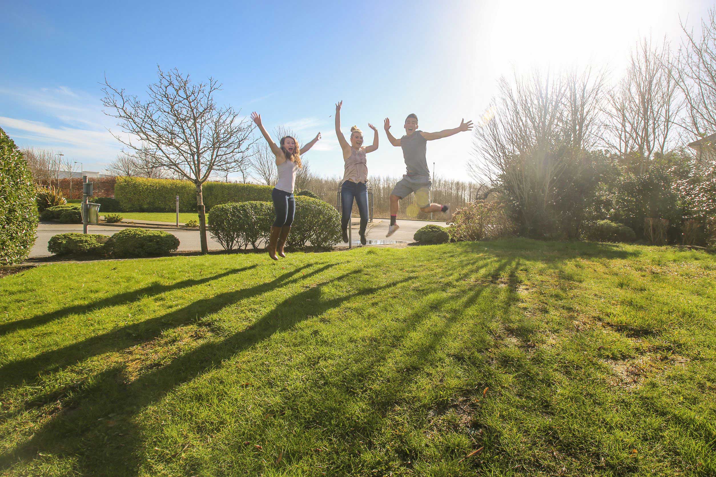 Three students jump in the sun while on the Galway, Ireland program.