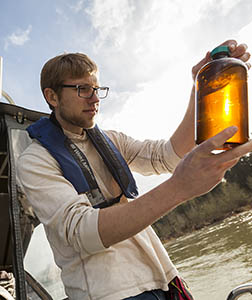 Student holding specimen jar of river water