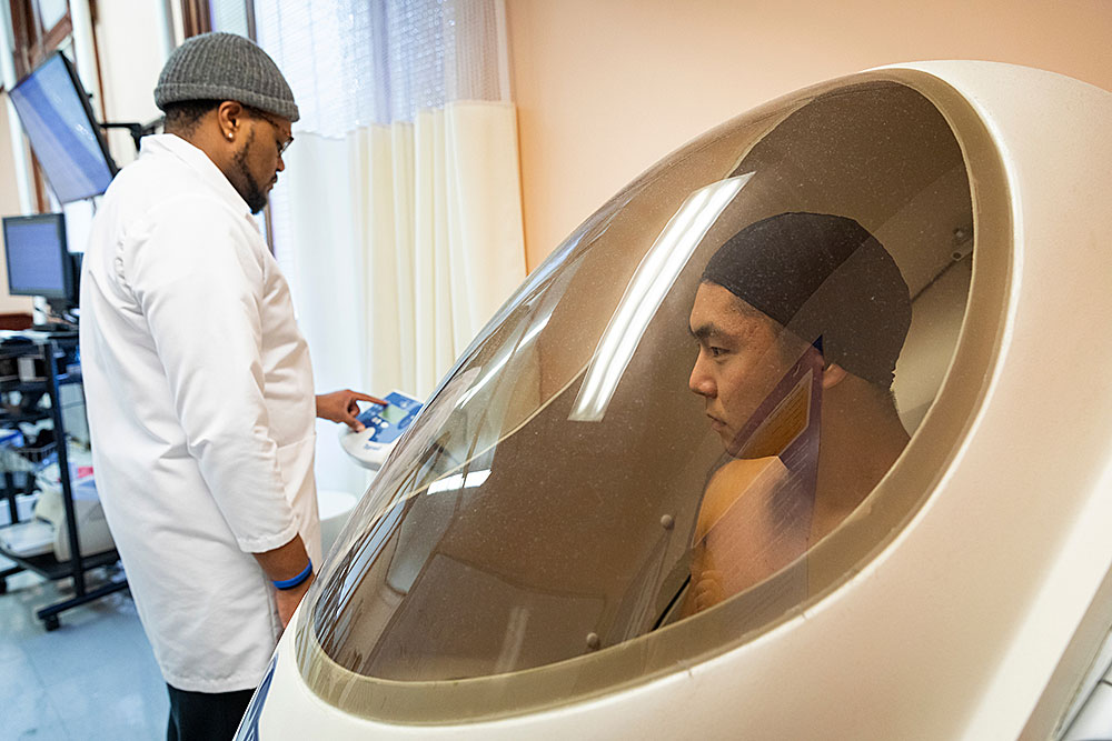 a student conducts body composition measurements with another student using a BodPod